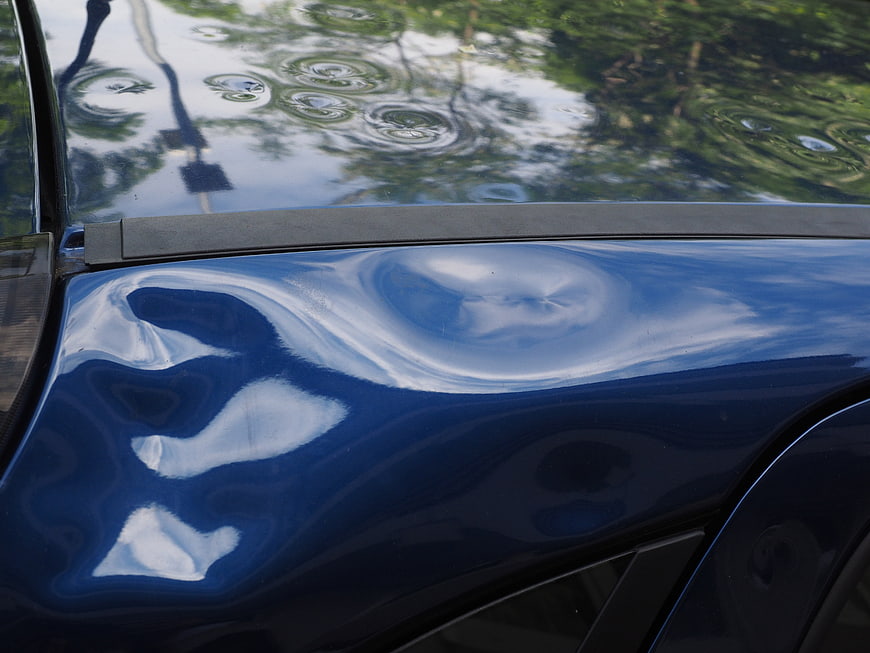 Close-up of hail damage dents on a blue car roof