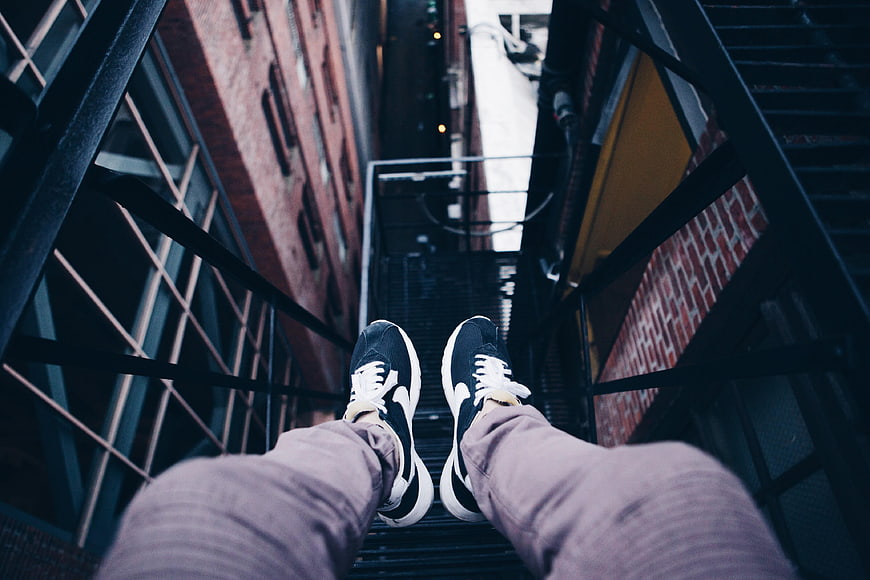 First-person view of sneakers on urban fire escape stairs