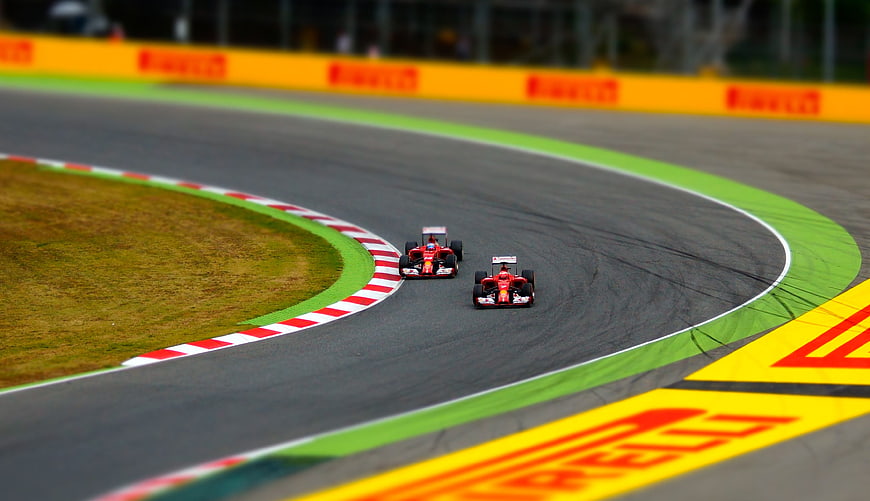 Two Red Formula 1 Cars Racing on a Curved Track