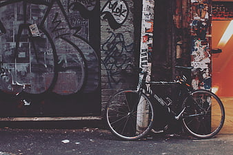 Black Bicycle Leaning Against Graffiti Wall