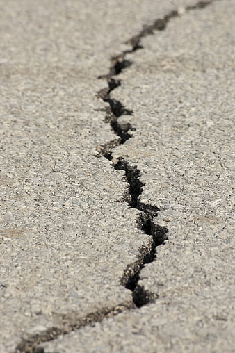 Close-up of a jagged crack in gray asphalt road surface