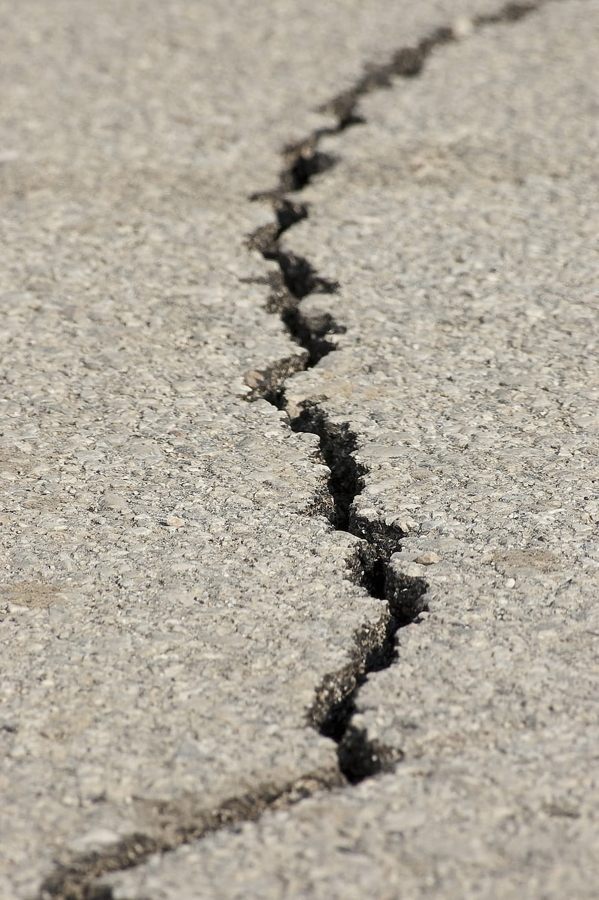 Close-up of a jagged crack in gray asphalt road surface