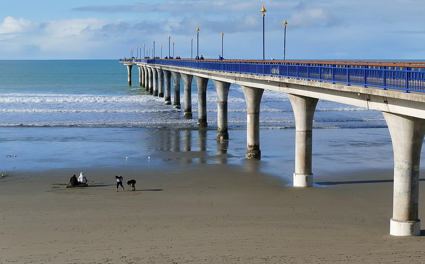 Blue Pier Extending Over Sandy Beach with Ocean Waves