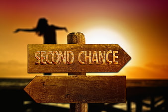Wooden sign reading second chance with silhouette at sunset