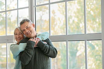 Happy Senior Couple Embracing by Window