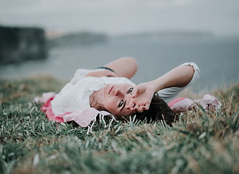 Young woman lying on grass looking at camera