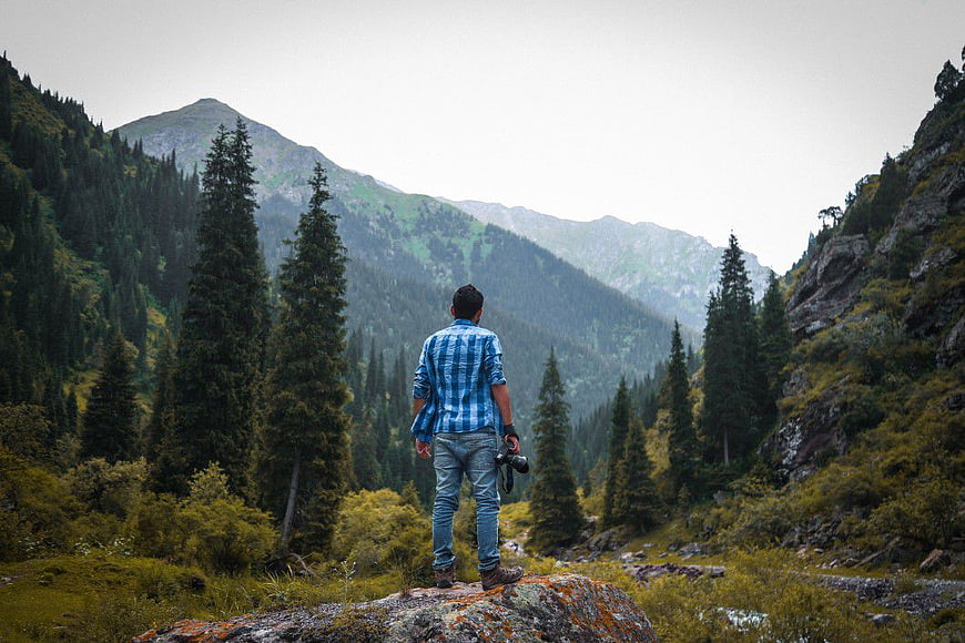 Male Photographer Standing on Rock in Mountain Forest