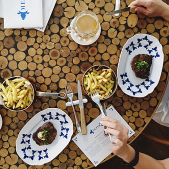 Top view of beef steaks and french fries on a wooden table