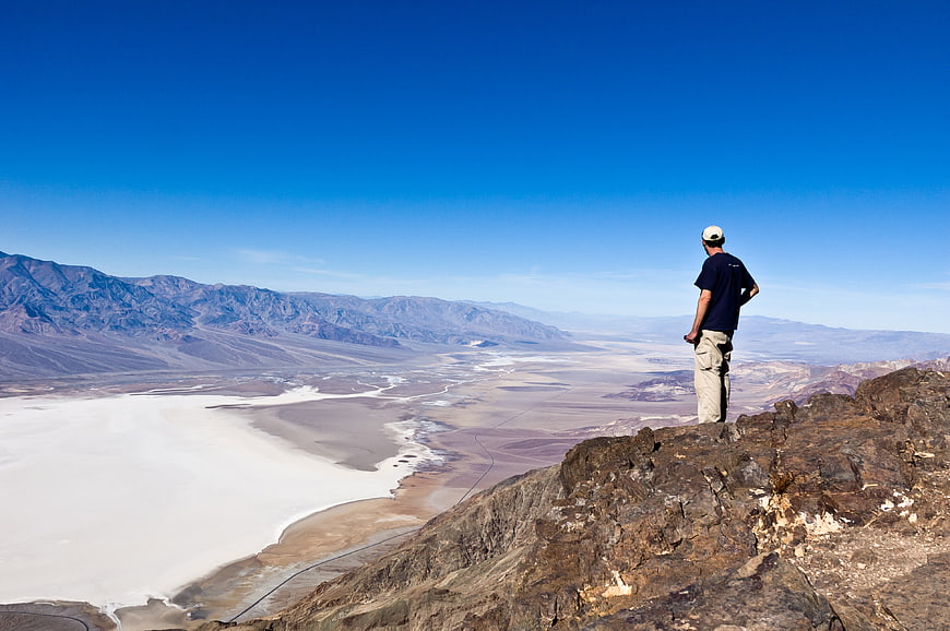 Hiker overlooking Death Valley desert landscape from rocky cliff