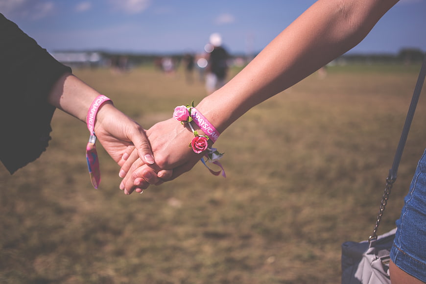 Couple holding hands with pink wristbands at outdoor festival