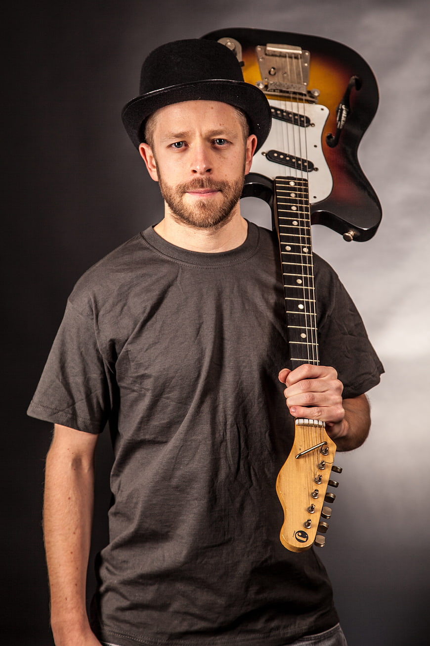 Male musician with bowler hat holding electric guitar