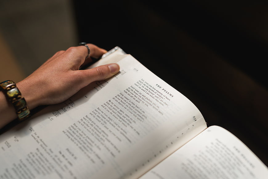 Hand holding open Bible with Psalms text visible