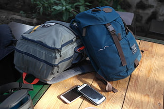Two Travel Backpacks And Smartphones On Wooden Table