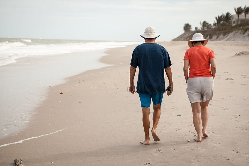 Senior couple walking barefoot on a quiet sandy beach