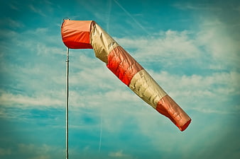 Orange and white windsock against blue sky