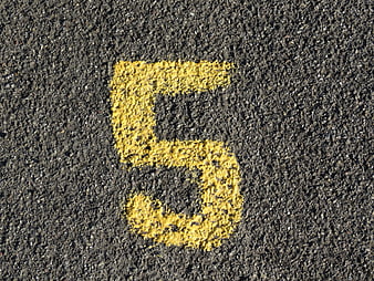 Yellow Number 5 Painted On Rough Asphalt Road Surface