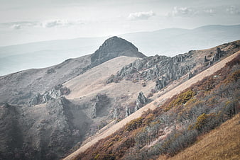 Misty autumn mountain landscape with rocky peaks and dry grass