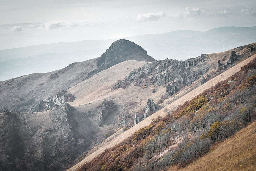 Misty autumn mountain landscape with rocky peaks and dry grass