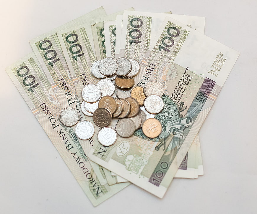 Pile of Polish 100 Zloty Banknotes and Coins on White Background