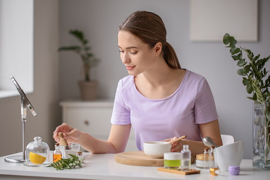 Woman making natural face mask with herbs and mortar