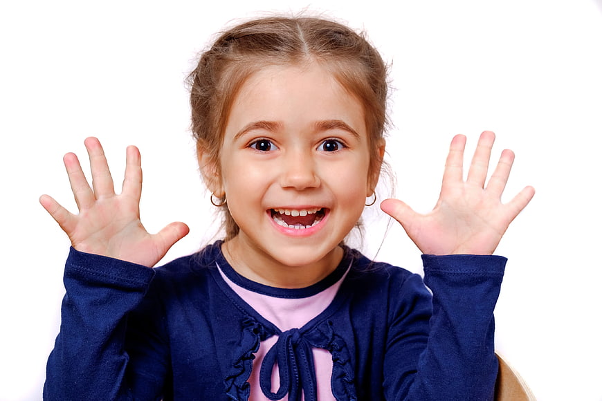 Happy little girl smiling with hands raised white background