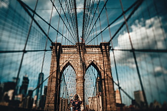 Woman taking photo of Brooklyn Bridge with city skyline
