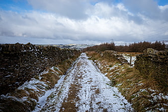 Snowy rural path between stone walls in winter countryside
