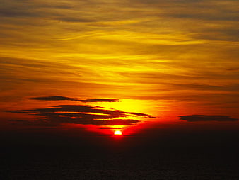 Vibrant Orange Sunset Over Ocean with Dramatic Clouds