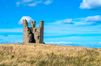 Dunstanburgh Castle Ruins on Grassy Hill Under Blue Sky