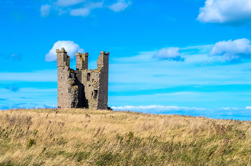 Dunstanburgh Castle Ruins on Grassy Hill Under Blue Sky