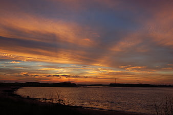 Dramatic sunset over water with orange and purple clouds