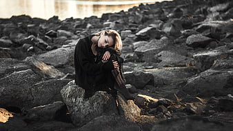 Melancholic Woman Sitting Alone On Rocky Shoreline