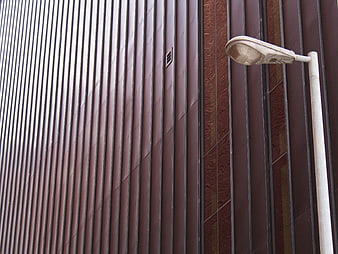 Modern brown corrugated metal building facade with street lamp