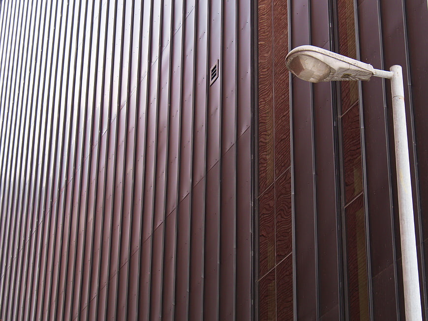 Modern brown corrugated metal building facade with street lamp