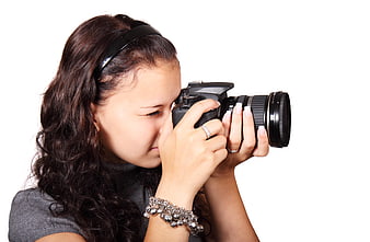 Young woman holding a digital SLR camera against a white background