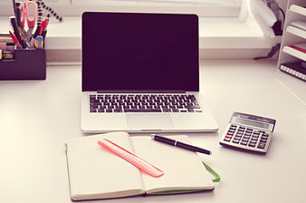 Modern office desk with laptop, notebook, and calculator