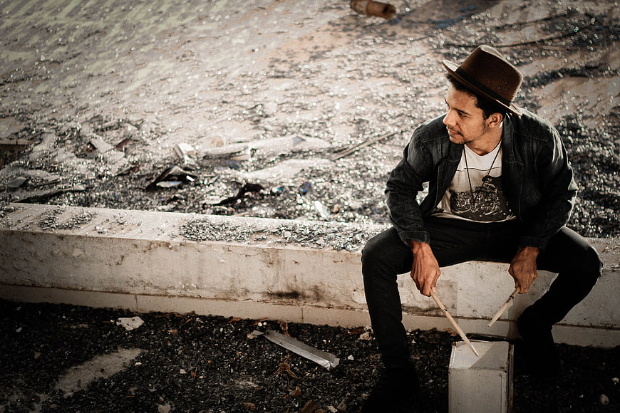 Man in Fedora Playing Drum Sticks on Rooftop