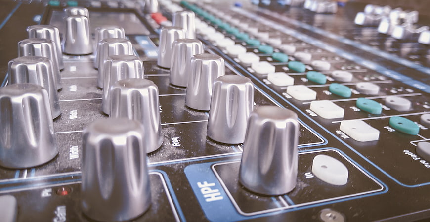 Close-up of professional audio mixing console knobs and sliders