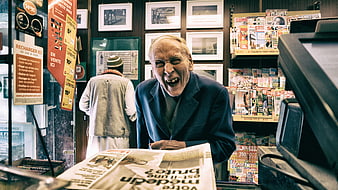 Laughing Senior Man Reading Newspaper in French Kiosk