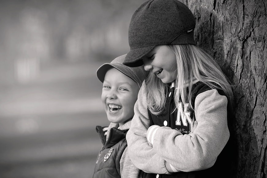 Laughing Boy and Girl Leaning Against Tree