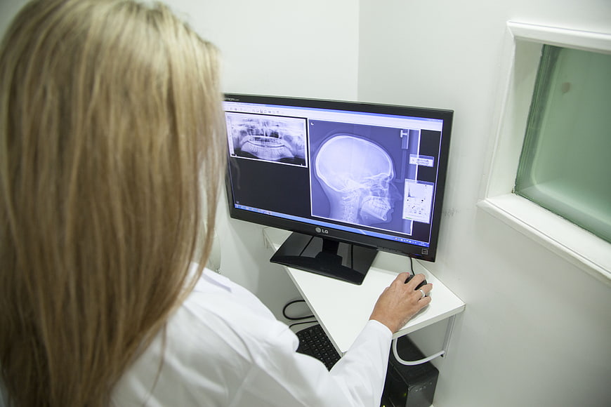 Dentist analyzing dental X-rays on computer monitor