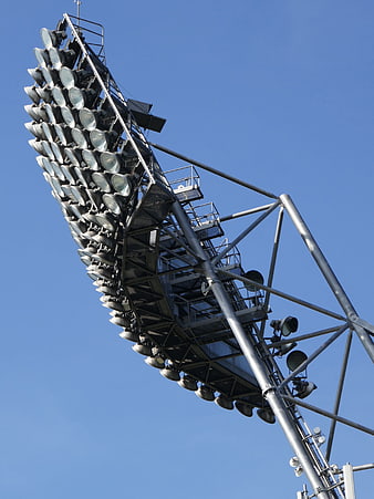 Low angle view of stadium floodlights against blue sky