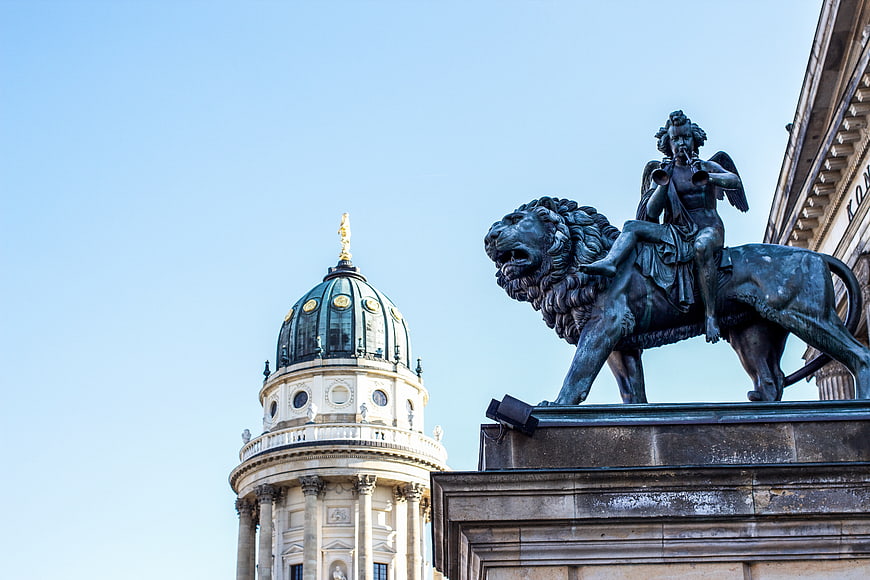 Berlin Cathedral Dome and Lion Statue Against Blue Sky