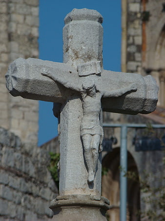 Weathered Stone Crucifix Sculpture Against Blue Sky