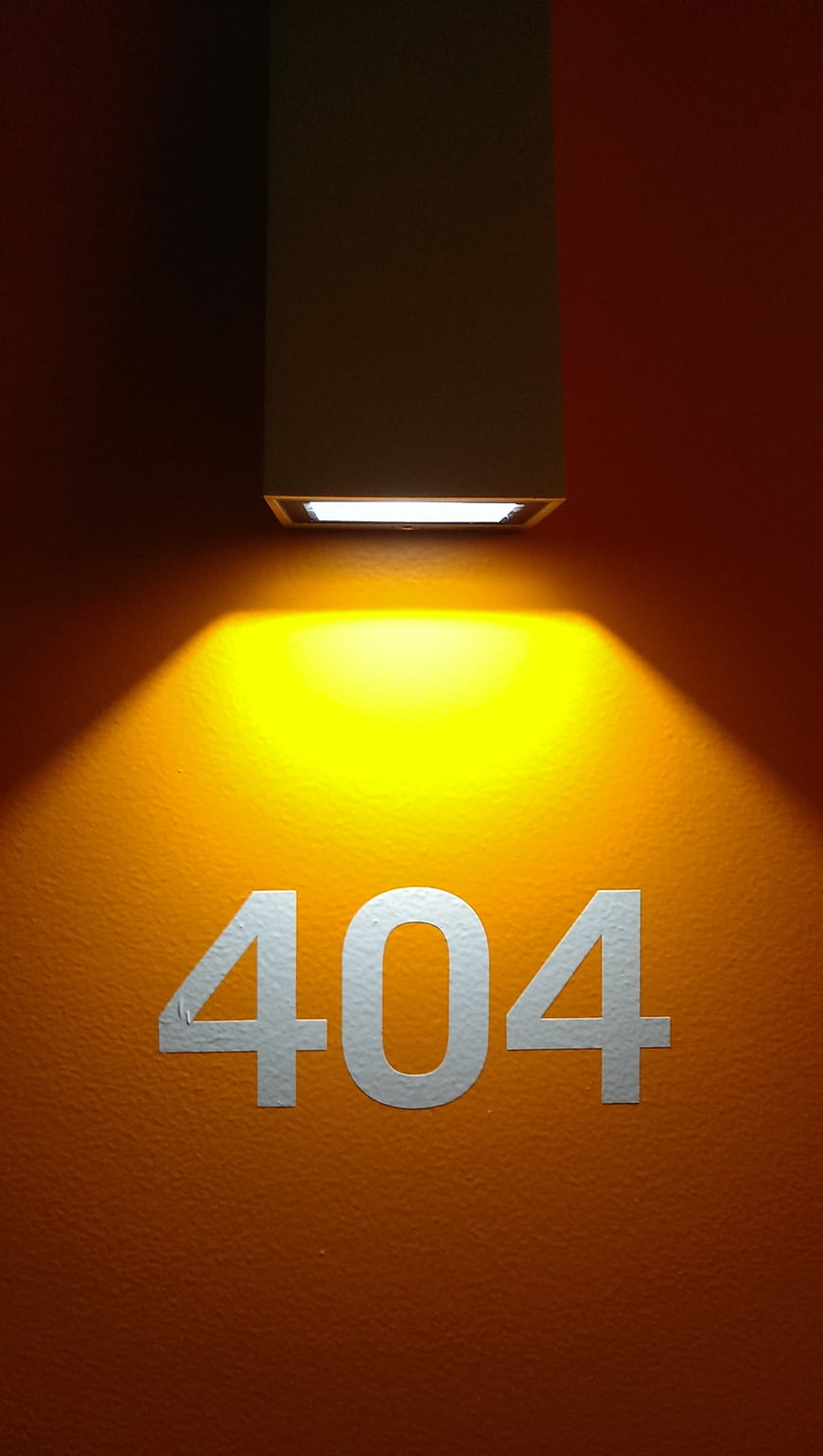 Illuminated 404 Room Number On Textured Orange Wall