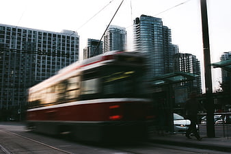 Motion blur of red city tram passing modern high-rise buildings