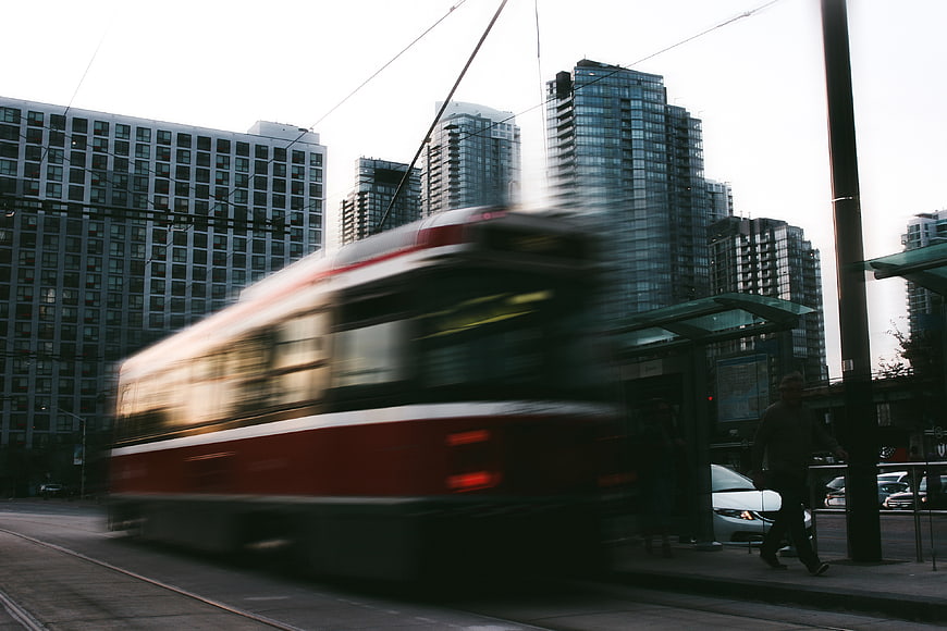 Motion blur of red city tram passing modern high-rise buildings