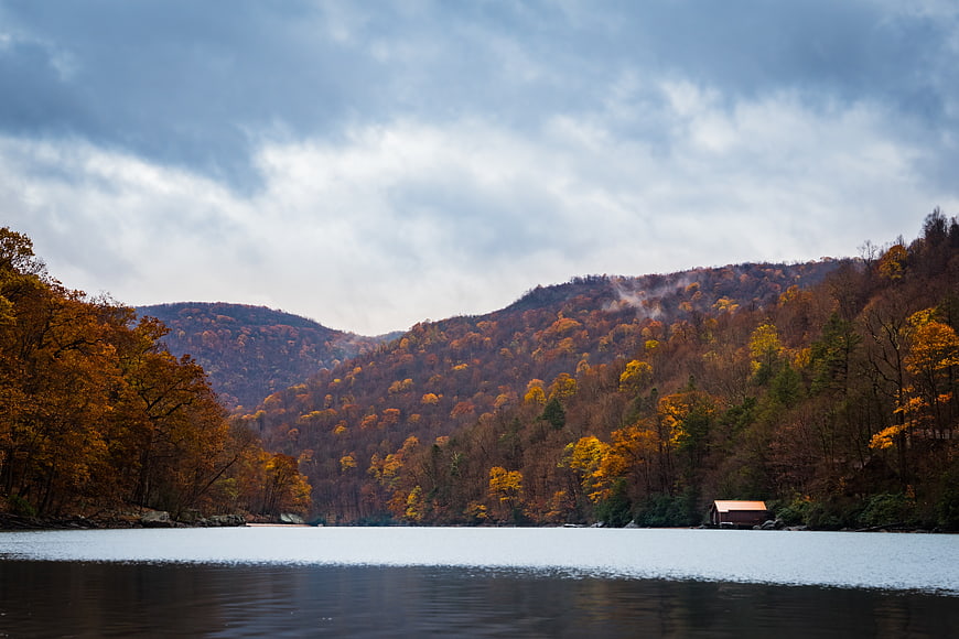 Serene Autumn Lake Landscape with Colorful Forest and Cabin