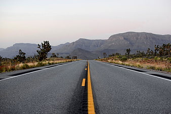 Empty Desert Highway Stretching Toward Distant Mountains