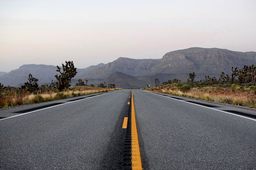 Empty Desert Highway Stretching Toward Distant Mountains